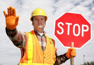 A construction worker stopping traffic, holding a stop sign.